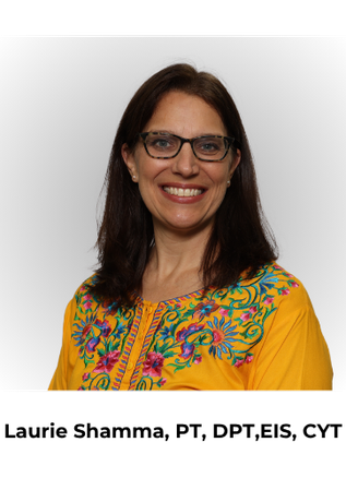 A woman with brown hair and glasses smiles at the camera, wearing a yellow blouse with floral embroidery.